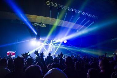 Parlak sahne ışıkları önünde konser kalabalığının siluetleri