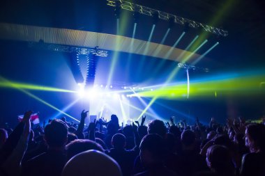 Parlak sahne ışıkları önünde konser kalabalığının siluetleri