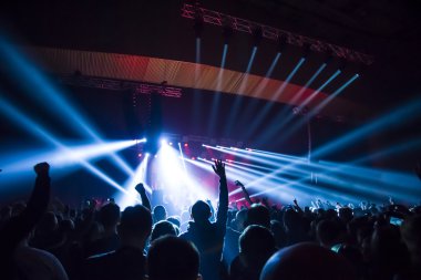 Parlak sahne ışıkları önünde konser kalabalığının siluetleri