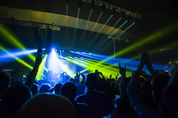 Parlak sahne ışıkları önünde konser kalabalığının siluetleri — Stok fotoğraf