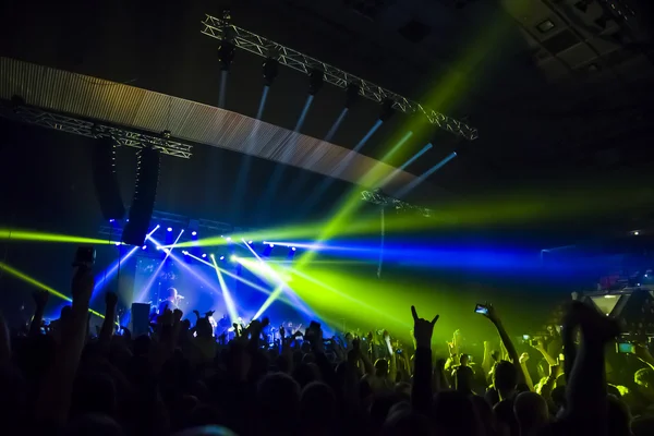 Parlak sahne ışıkları önünde konser kalabalığının siluetleri