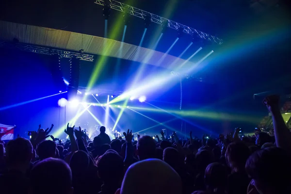 Parlak sahne ışıkları önünde konser kalabalığının siluetleri