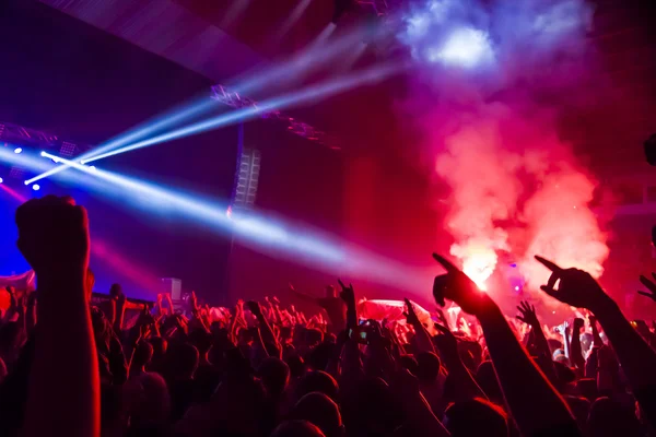 Parlak sahne ışıkları önünde konser kalabalığının siluetleri
