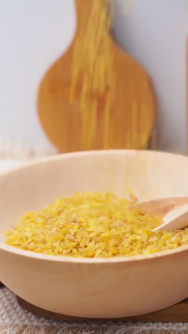 Bulgur in een houten kom op de achtergrond van een houten tafel, rustieke stijl. Bulgaarse tarwekorrels — Stockvideo