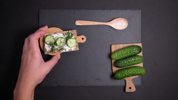 Knaprigt bröd med färsk gurka med dill och färskost, rustik ekologisk hälsosam smörgås. Ett platt ligg. vertikal video — Stockvideo