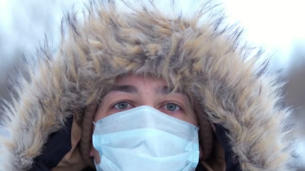 Портрет молодого чоловіка в медичній масці взимку. захист від вірусів — стокове відео