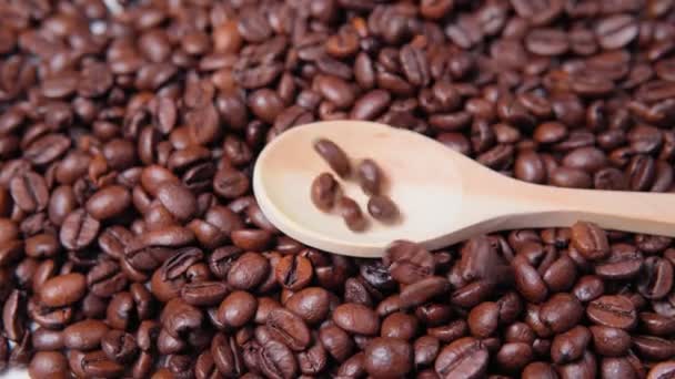 香り高いコーヒー豆が近くに落ちます。木製のスプーンコーヒー豆. — ストック動画