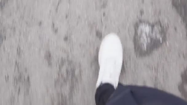 하얀 운동화를 신고 얼어붙은 아스팔트를 타고 겨울 길을 걷는 모습 — 비디오