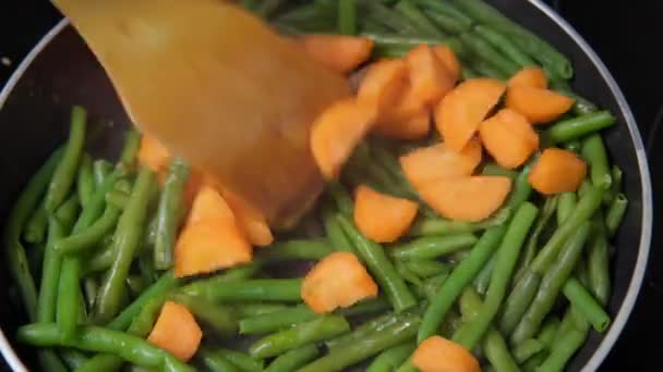 Zanahorias salteadas y habichuelas en una sartén de cerca. cocina comida vegetariana — Vídeo de stock