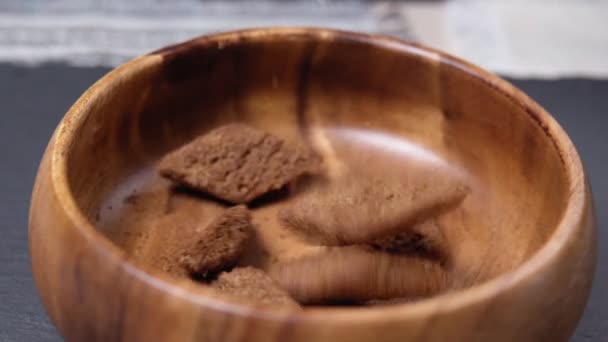 Los crutones en el plato castaño sobre la mesa de madera. Primer plano. Enfoque selectivo. cayendo en un tazón cámara lenta — Vídeos de Stock