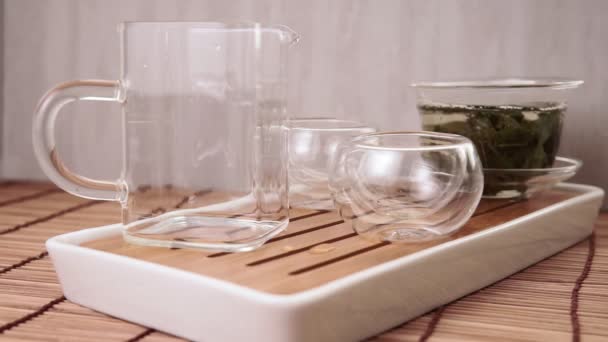 Kínai zöld teát önt egy üveg teáskanna egy kis csésze — Stock videók