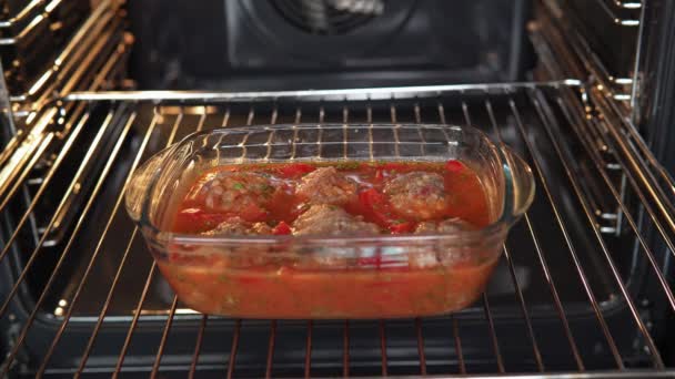 Albóndigas cocidas en forma en el horno con salsa de pasta de tomate, tomates, cebollas y especias. — Vídeo de stock