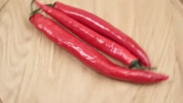 Rode hete chili pepers close-up spinnen op houten achtergrond — Stockvideo