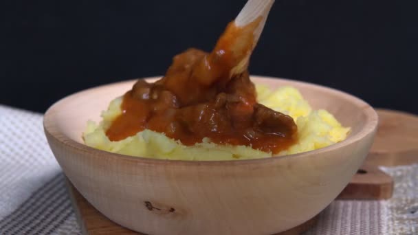 Menuangkan saus goulash dalam kentang tumbuk close-up. Sup rebusan daging sapi Hungaria tradisional Goulash — Stok Video