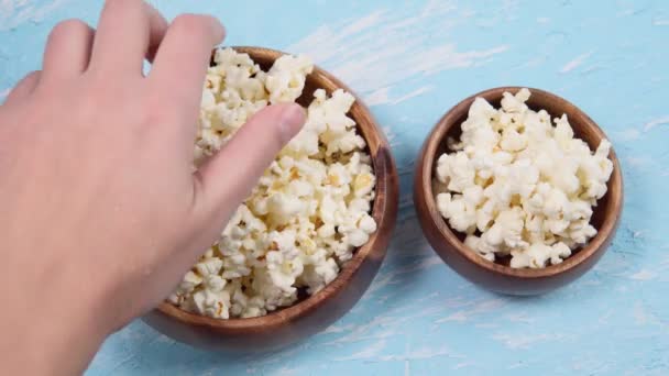 Popcorn v misce na modrém pozadí. ruka vezme popcorn close-up — Stock video