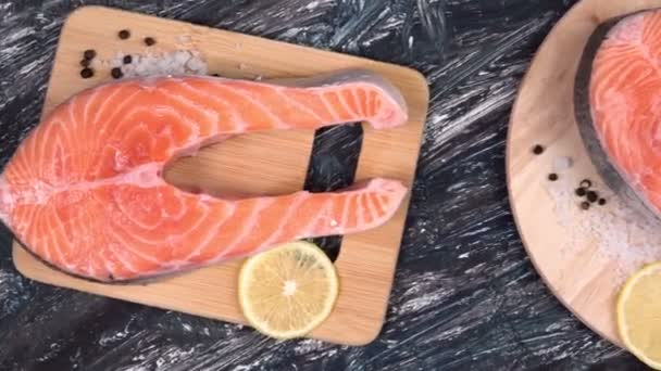 Bistecca di salmone crudo con ingredienti come limone, pepe, sale marino su un bordo nero. — Video Stock
