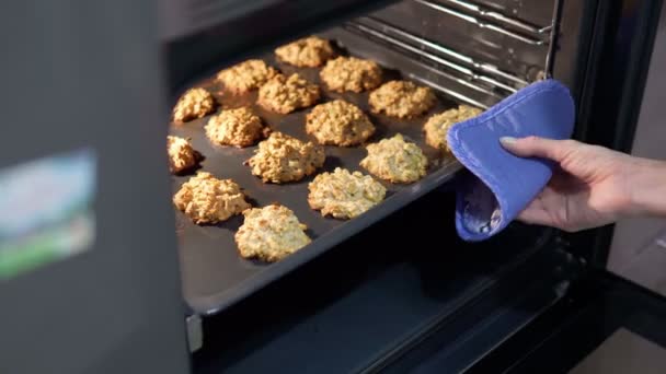 Kadın fırından lezzetli yulaflı kurabiyelerle fırın tepsisi alıyor. seçici odak — Stok video