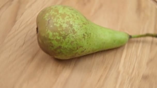 Nahaufnahme einer Fruchtbirne dreht sich auf einem Holztisch. — Stockvideo