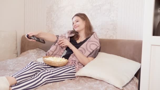 Mädchen sitzen auf dem Bett, essen Popcorn, sehen einen Comedy-Film im Fernsehen, entspannen zu Hause — Stockvideo