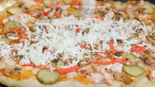 Saupoudrer le fromage sur la pizza avec des champignons concombres et poivre, mise au point sélective. pâte à pizza dans une cuisine. — Video