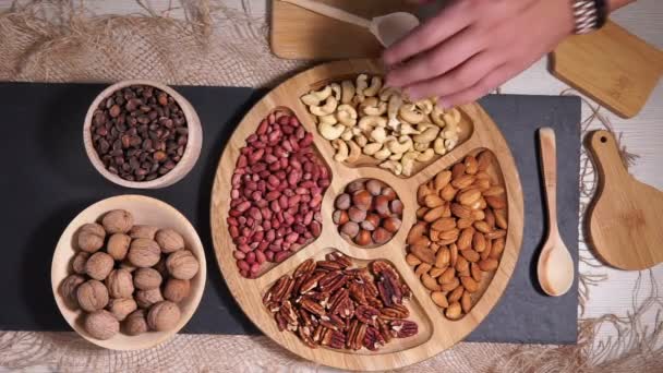 Pemilihan kacang tanah, hazelnut, almond, kacang mete, kenari, kacang pikan di atas meja kayu. Tampilan atas dengan spasi untuk teks Anda — Stok Video