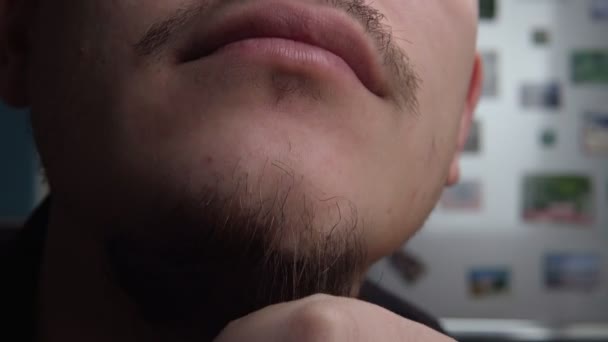 Jongeman krabt zijn baard ongeschoren mannelijke gezicht van dichtbij. selectieve close-up-focus — Stockvideo