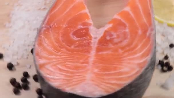 Сырой стейк лосося близко - до вращения на деревянном фоне — стоковое видео