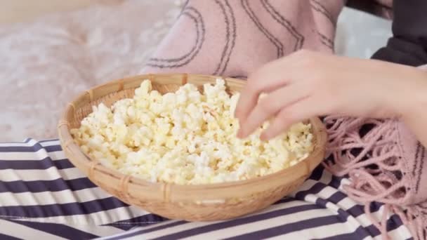 Närbild av kvinnlig hand tar popcorn från stora glas medan du tittar på film hemma. — Stockvideo