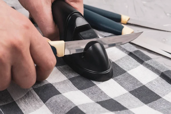 man is sharpening kitchen knives. sharpening a knife with a home sharpener