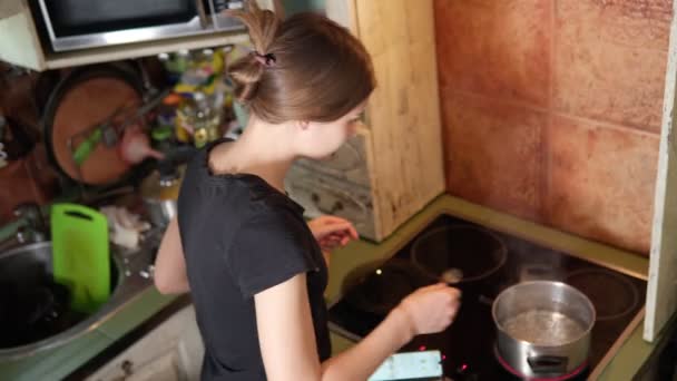 Mladá žena se připravuje v kuchyni. recept z vašeho chytrého telefonu. Zdravý životní styl. Vaření doma. — Stock video