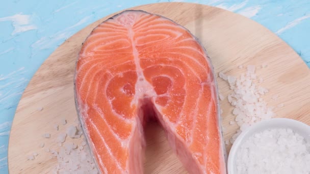Bife cru de salmão em um fundo de pedra azul. a adição de especiarias pimenta preta — Vídeo de Stock