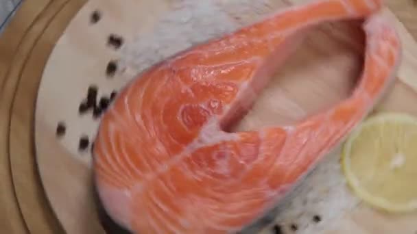 Bistecca di salmone crudo con ingredienti come limone, pepe, sale marino a bordo. — Video Stock