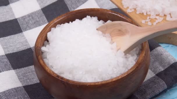 Белая морская соль в натуральной деревянной чаше на голубом фоне. Селективный фокус. — стоковое видео