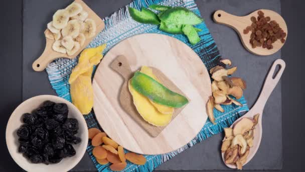 Suszone owoce w drewnianym talerzu. mango, jabłka, śliwki, suszone morele feijoa. zdrowe przekąski. widok z góry — Wideo stockowe
