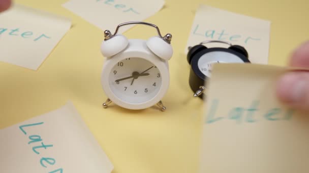 Relógio despertador com uma nota pegajosa com texto mais tarde. Conceito de procrastinação, atraso e urgência. — Vídeo de Stock