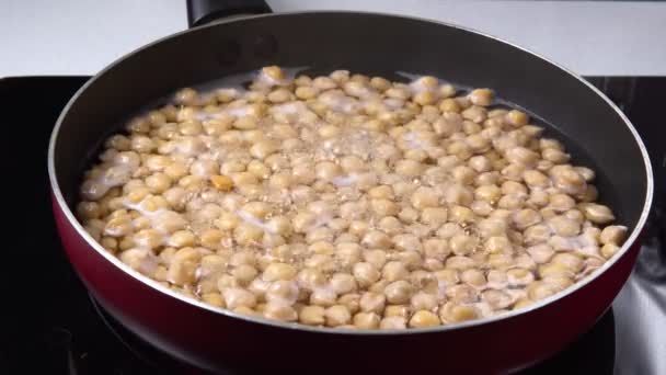 Cooking chickpeas in hot water. Dry garbanzo beans submerged in water.