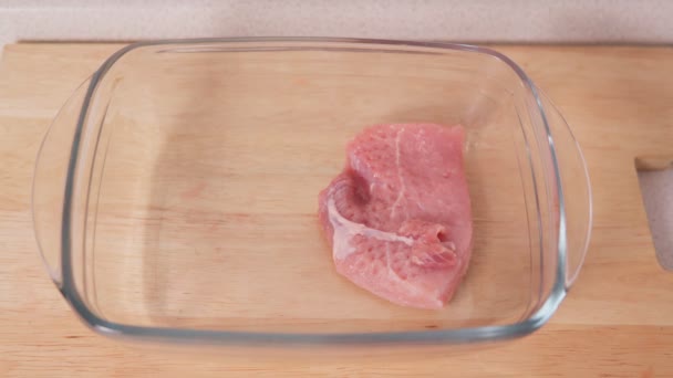 Bifes de porco são colocados em uma assadeira. cozinhar alimentos — Vídeo de Stock