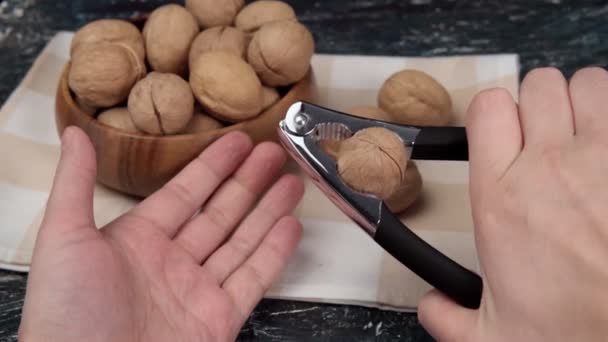 Hand cracking walnuts. walnuts and shells on a wooden table. selective focus — Stock Video
