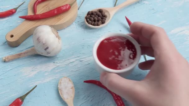 Piros chilis csípős paprika szósz kék háttérrel. A szósz előkészítése — Stock videók