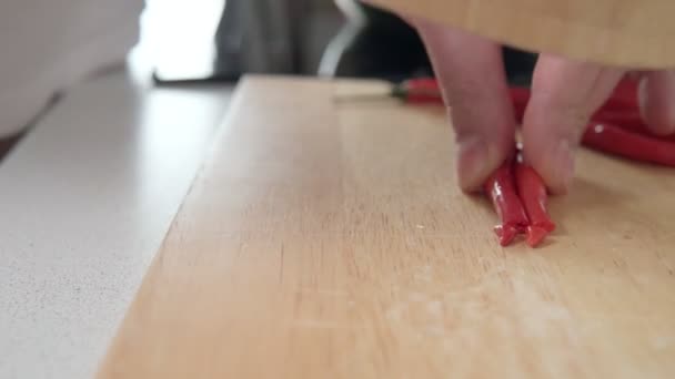 Άνθρωπος τεμαχισμός πιπεριές τσίλι, κοντινό βίντεο, ρουστίκ ξύλινο — Αρχείο Βίντεο
