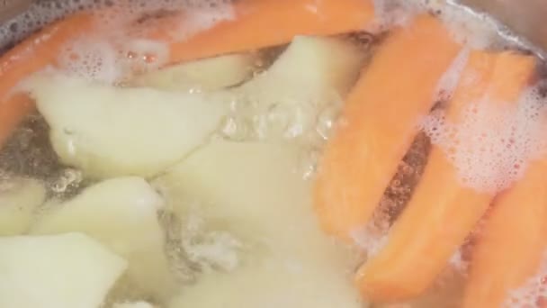 Gemüse in Wasser. Möhren und Kartoffeln in einer Pfanne in Großaufnahme. Gemüsesuppe kochen. Vegetarisches Kochen — Stockvideo