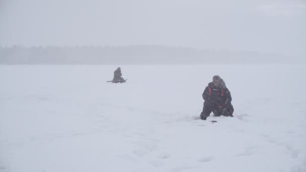 Pescadores pegar peixes no inverno em nevasca pesada. foco suave — Vídeo de Stock