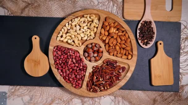 Nueces mezcladas sobre un fondo oscuro. Comida saludable y aperitivos. Pecanas, anacardos, almendras, cacahuetes, piñones, avellanas — Vídeos de Stock