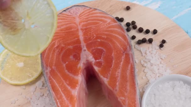 Filetes de salmón crudo con limón sobre un fondo de piedra azul. — Vídeo de stock