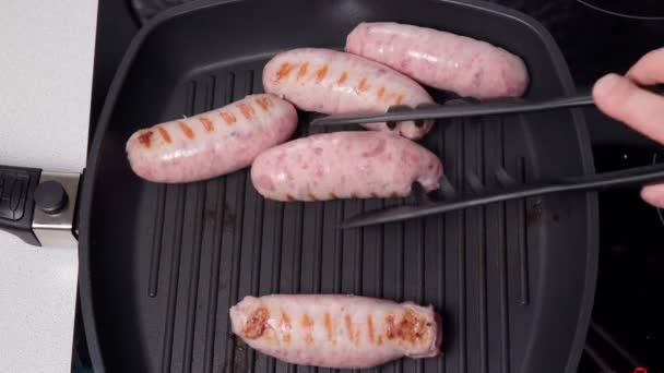 Cuisson des saucisses en gros plan sur une poêle à griller. Cuisine vue sur le dessus des aliments. vidéo verticale — Video