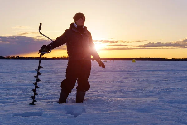 年轻的长胡子千年男子在黎明时分在一个冬季的湖上钓鱼 清晨冬季钓鱼 — 图库照片