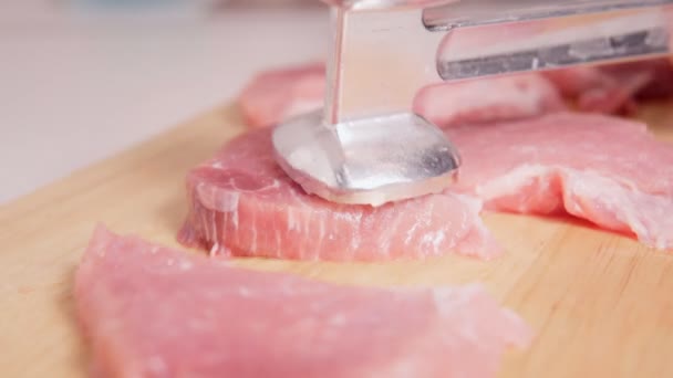 As partes cruas da carne de porco batem-se com um martelo de cozinha em uma tábua de madeira antes de cozinhar. carne fresca em bruto — Vídeo de Stock