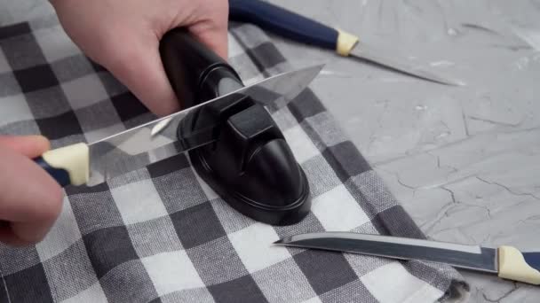 El hombre está afilando cuchillos de cocina. afilando un cuchillo con un sacapuntas. enfoque selectivo — Vídeo de stock