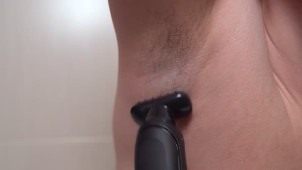 Male depilation. Young man using razor to remove hair from his armpit — Stock Video