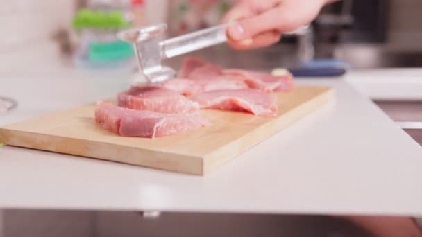 Cozinhar costeletas de carne de porco. As partes cruas da carne de porco batem-se com um martelo de cozinha em uma tábua de madeira antes de cozinhar. carne fresca em bruto — Vídeo de Stock
